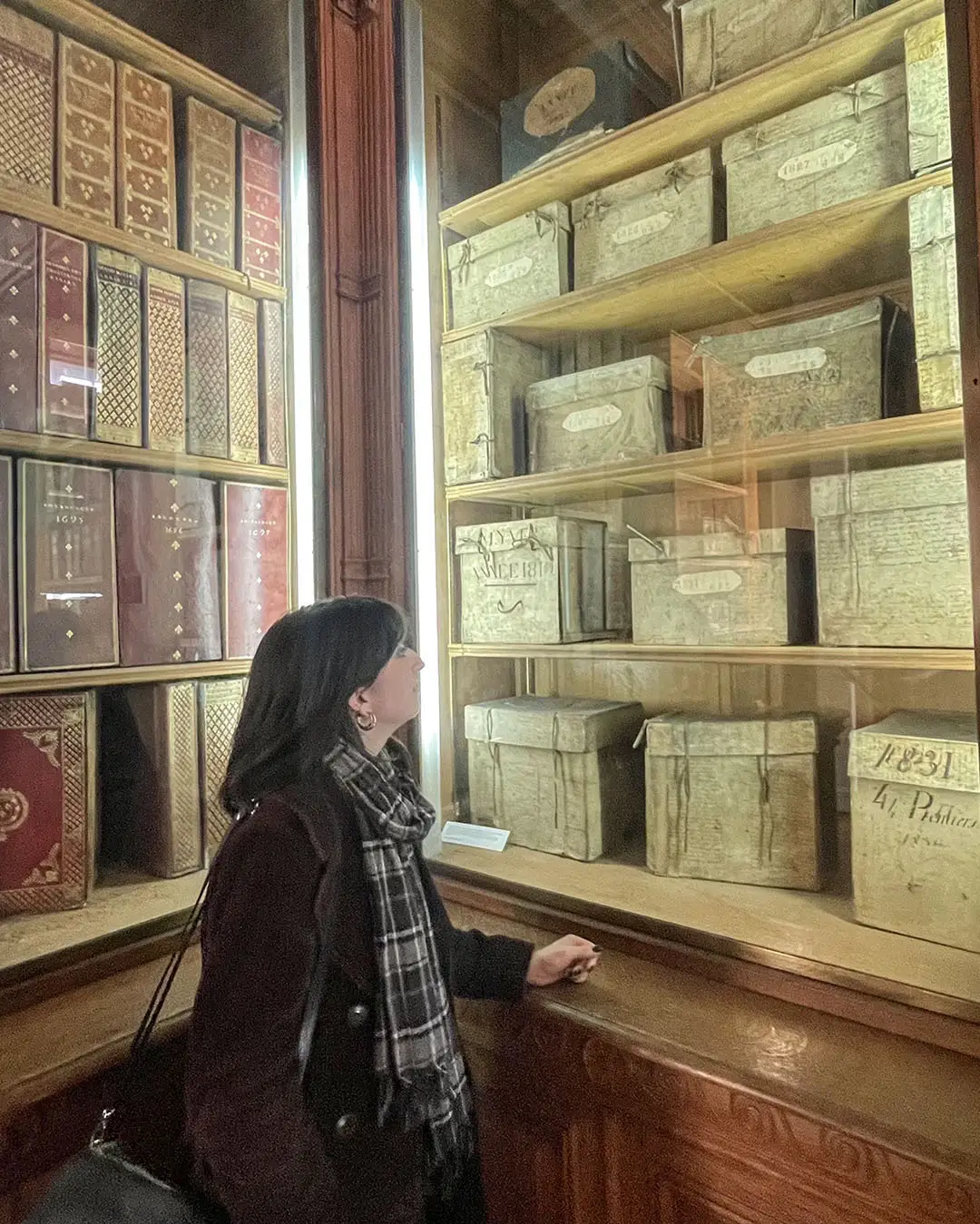 Laurie looking at shelves of antique bound registers and archive boxes in a historical library