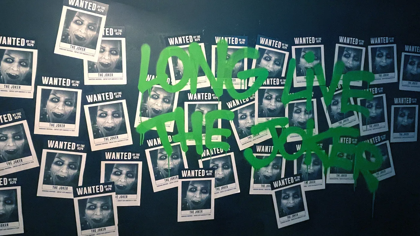 Wall covered in Joker Wanted posters with Long Live the Joker graffiti