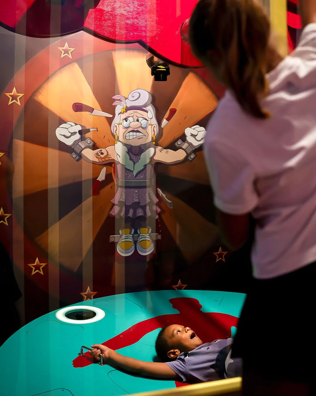Child playing the Human Target attraction on a rotating platform below a cartoon Micheline target wheel