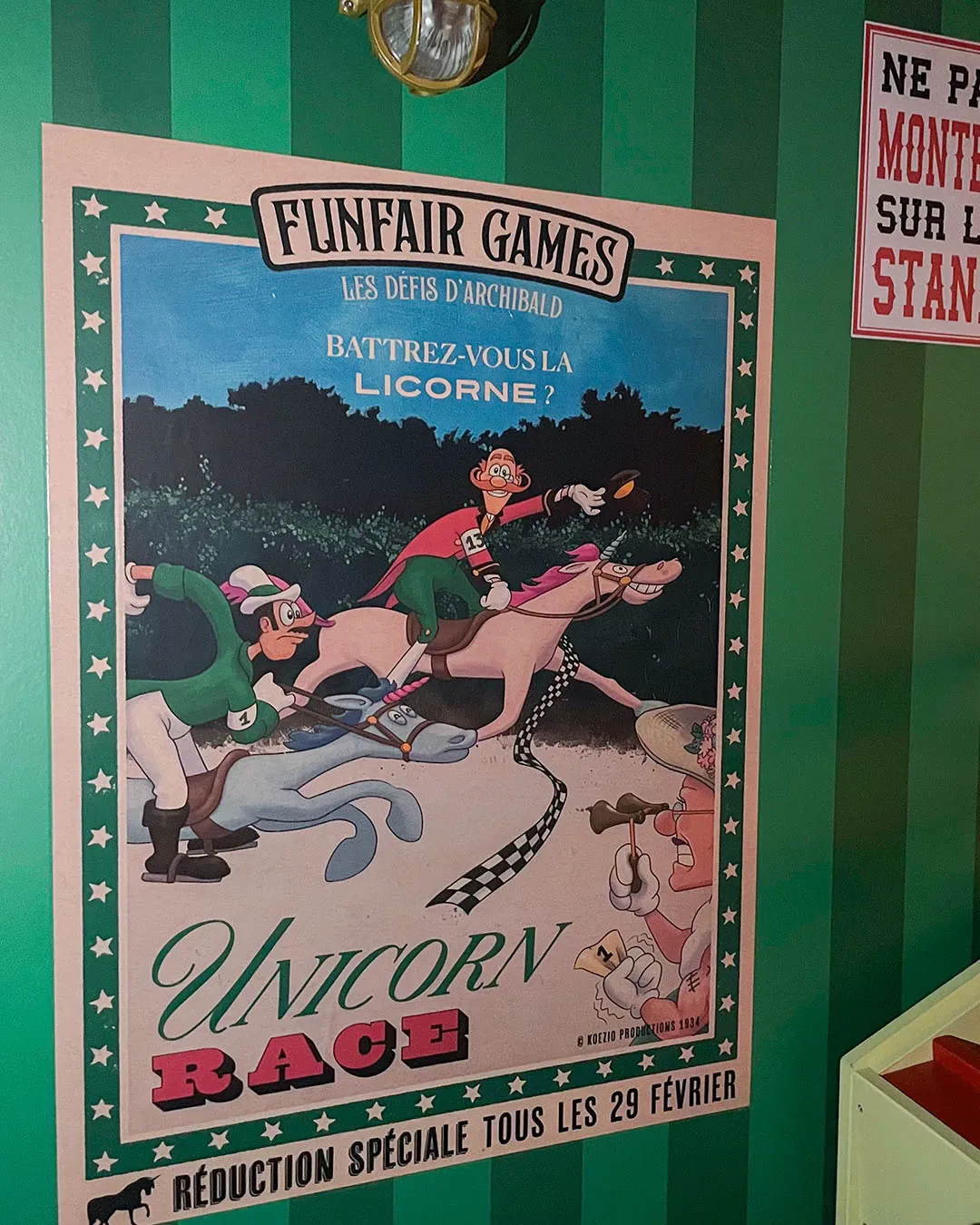 Unicorn Race poster installed on a green striped wall, with jockeys racing unicorns