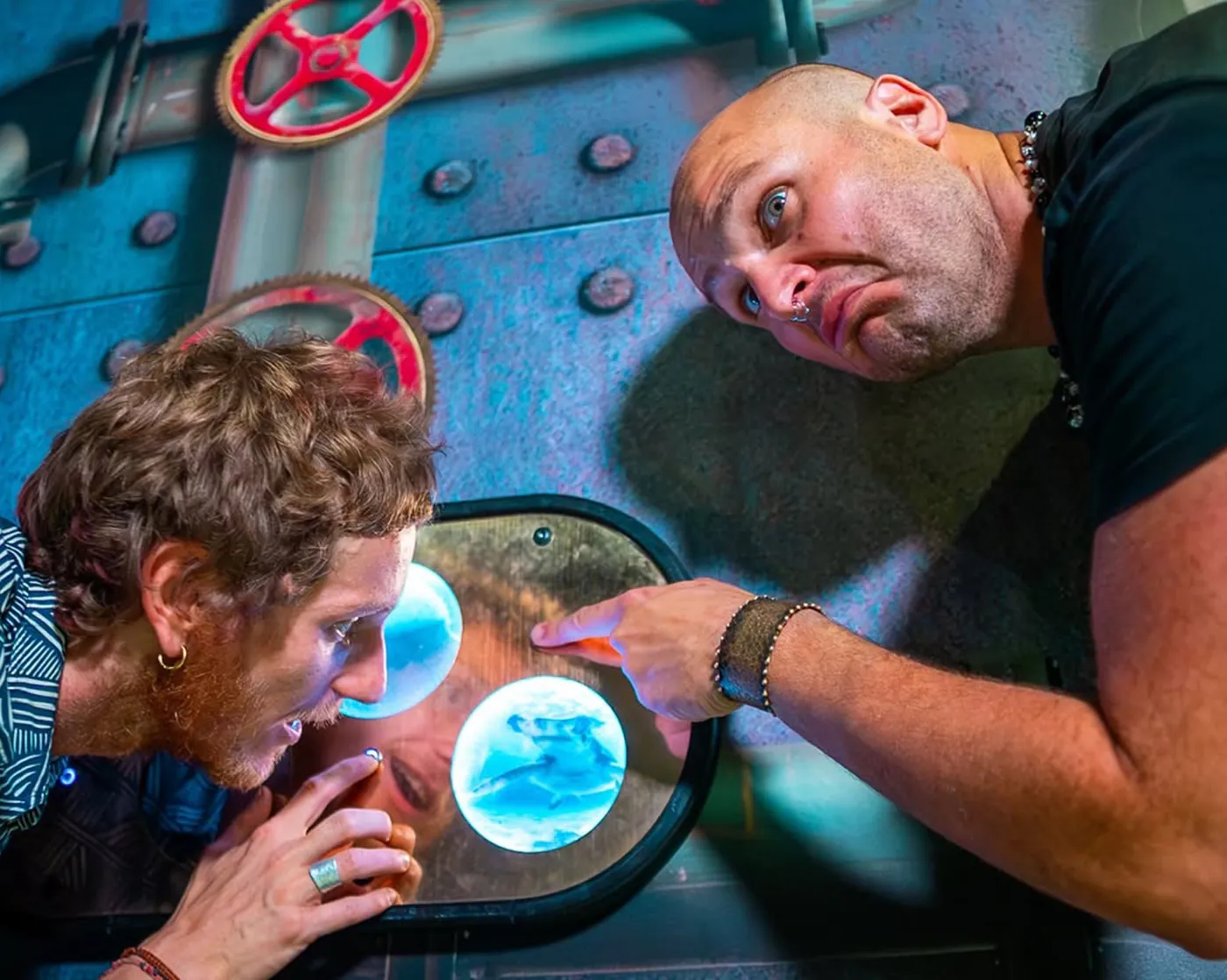 Two players examining a glowing porthole inside the steampunk submarine room