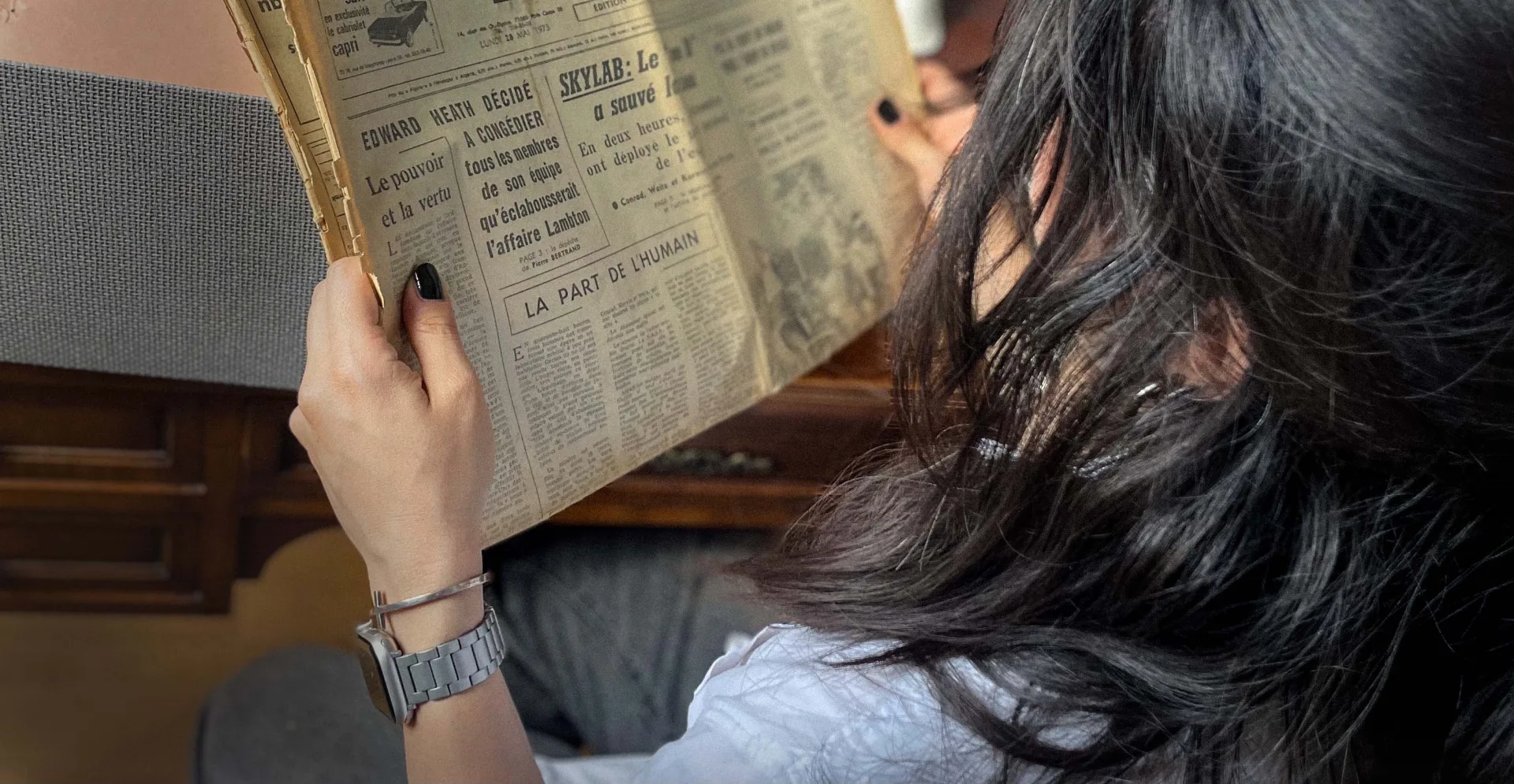 Une femme lit un vieux journal de fiction dans une lumière chaude.