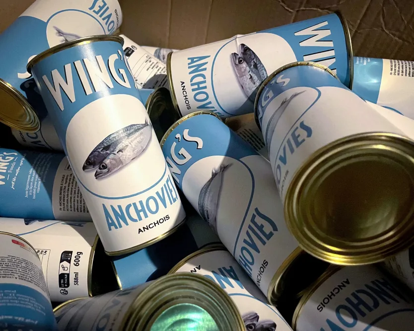 Une caisse de boîtes d'anchois de fiction « Wings », étiquettes gravées à dirigeable.