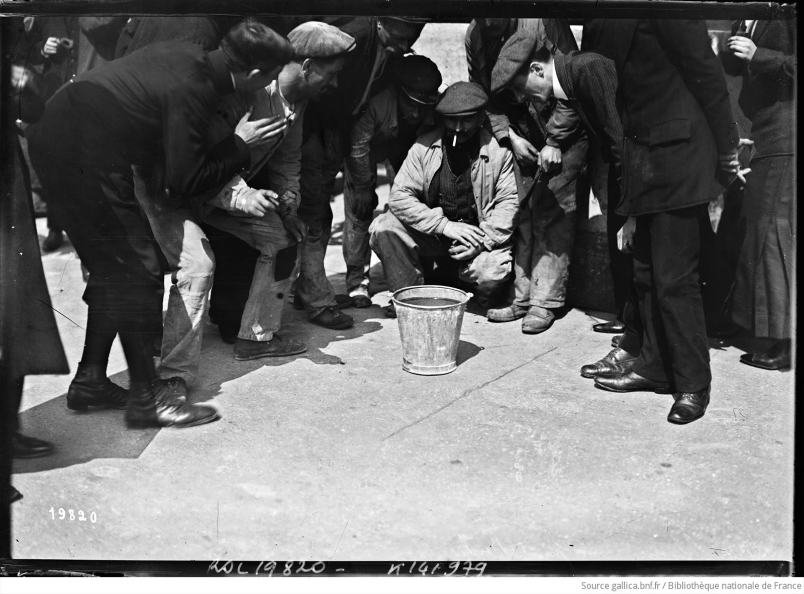 17 avril 1912, éclipse de soleil à Paris, Grands Boulevards, personnes assemblées regardant dans un seau d'eau. Photographie de presse, Agence Rol
